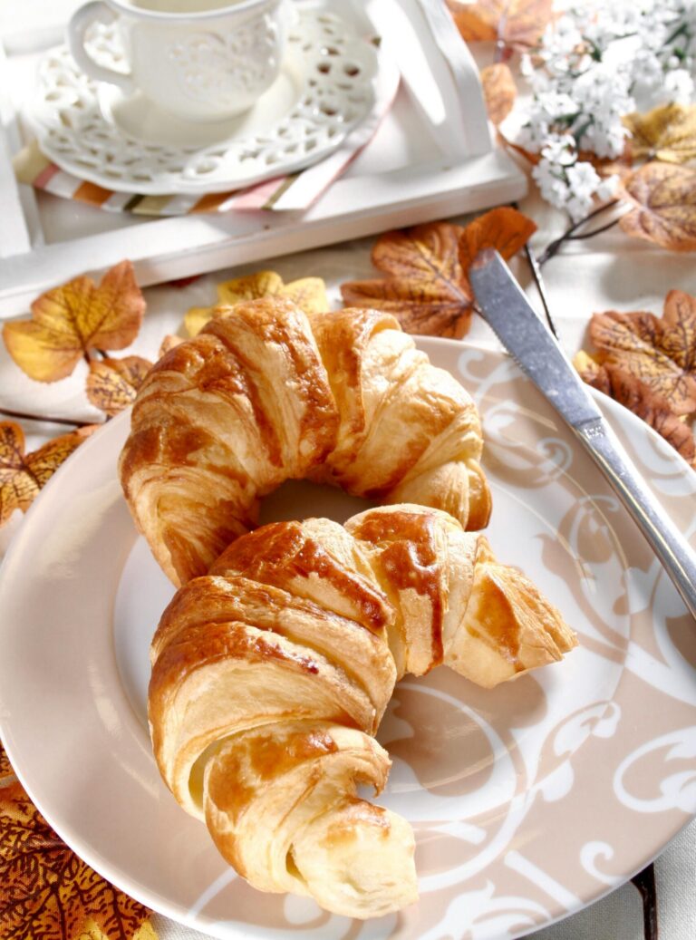 Delicious fresh croissants served with a cup of coffee, perfect for a cozy fall breakfast.